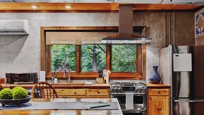 A modern kitchen with a large window, stainless steel appliances, and wooden cabinetry.