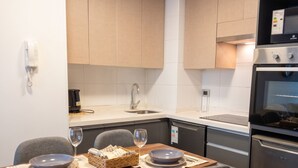 A modern kitchen with a dining area, stainless steel appliances, and a clean, minimalist design. - Santiago Barrio Italia - Domus Travels (Santiago)