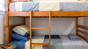 A bunk bed with a ladder, a small table with a notebook and pen, and a window with blinds. - Santiago Barrio Italia - Domus Travels (Santiago)