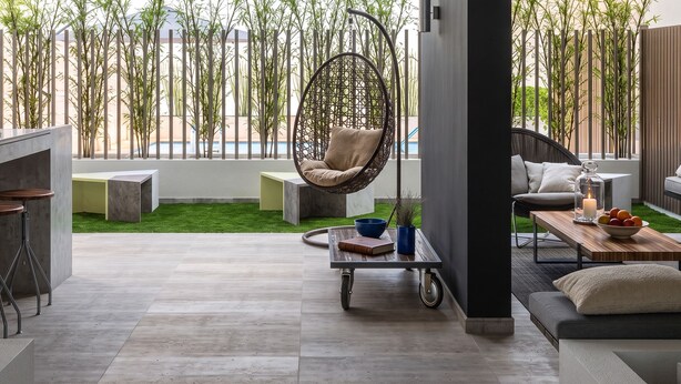 A modern interior with a hanging chair, a sofa, a dining table, and a bar area with stools. - Santiago Barrio Italia - Domus Travels (Santiago)