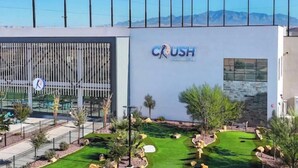 A modern building with a sign that reads 'CRUSH' and a well-maintained outdoor area with grass, rocks, and trees. -  DesertColor St. George Spacious 4-bedroom house pool & hot tub front door steps (St. George)
