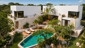 A modern two-story house with a swimming pool, stone walls, and outdoor seating. - VillaLaGrieta: Luxury Eco-Villa, Lagoon &Cenotes access, Ocean Views in Akumal (AKUMAL)