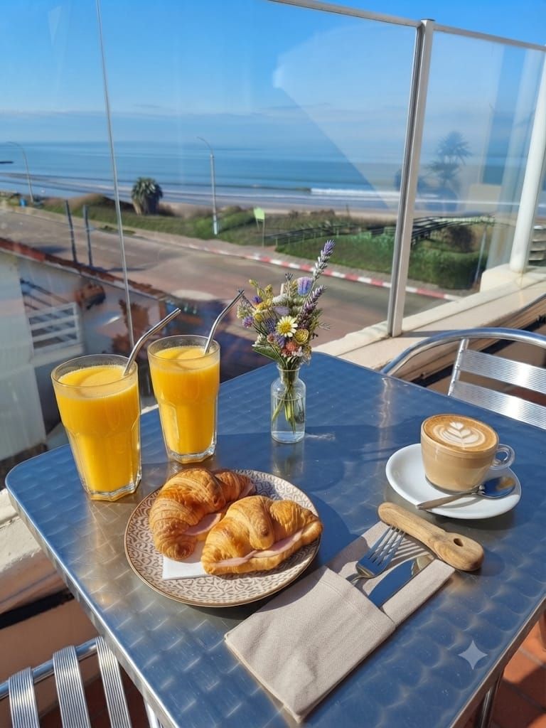 A table with breakfast items, a glass of orange juice, a coffee cup, and a croissant plate.