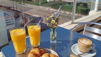 A table with breakfast items, a glass of orange juice, a coffee cup, and a croissant plate.