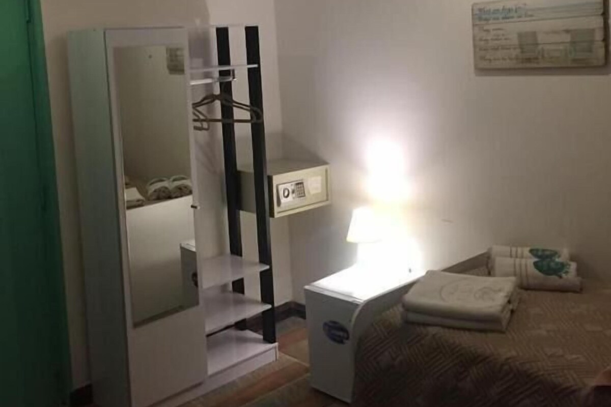 Un dormitorio con cama, mesita de noche, lámpara, armario y espejo.