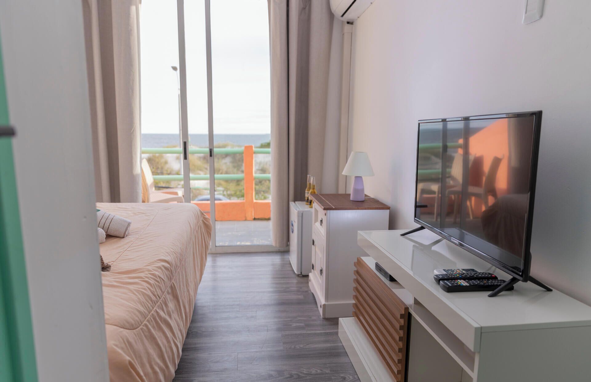 A hotel room with a bed, a TV, a lamp, and a view of the outdoors.