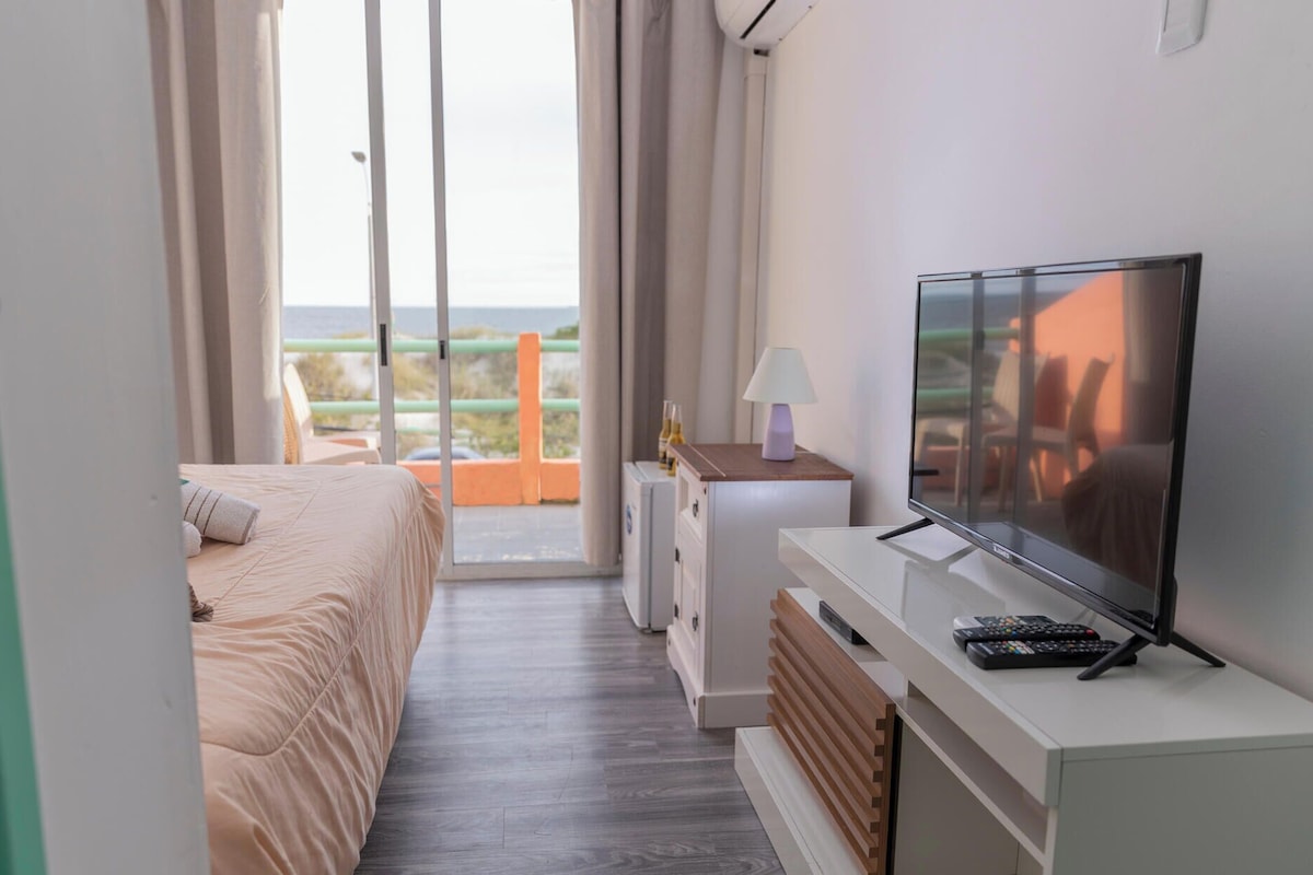 Habitación de hotel con cama, televisión, lámpara y vistas al exterior.