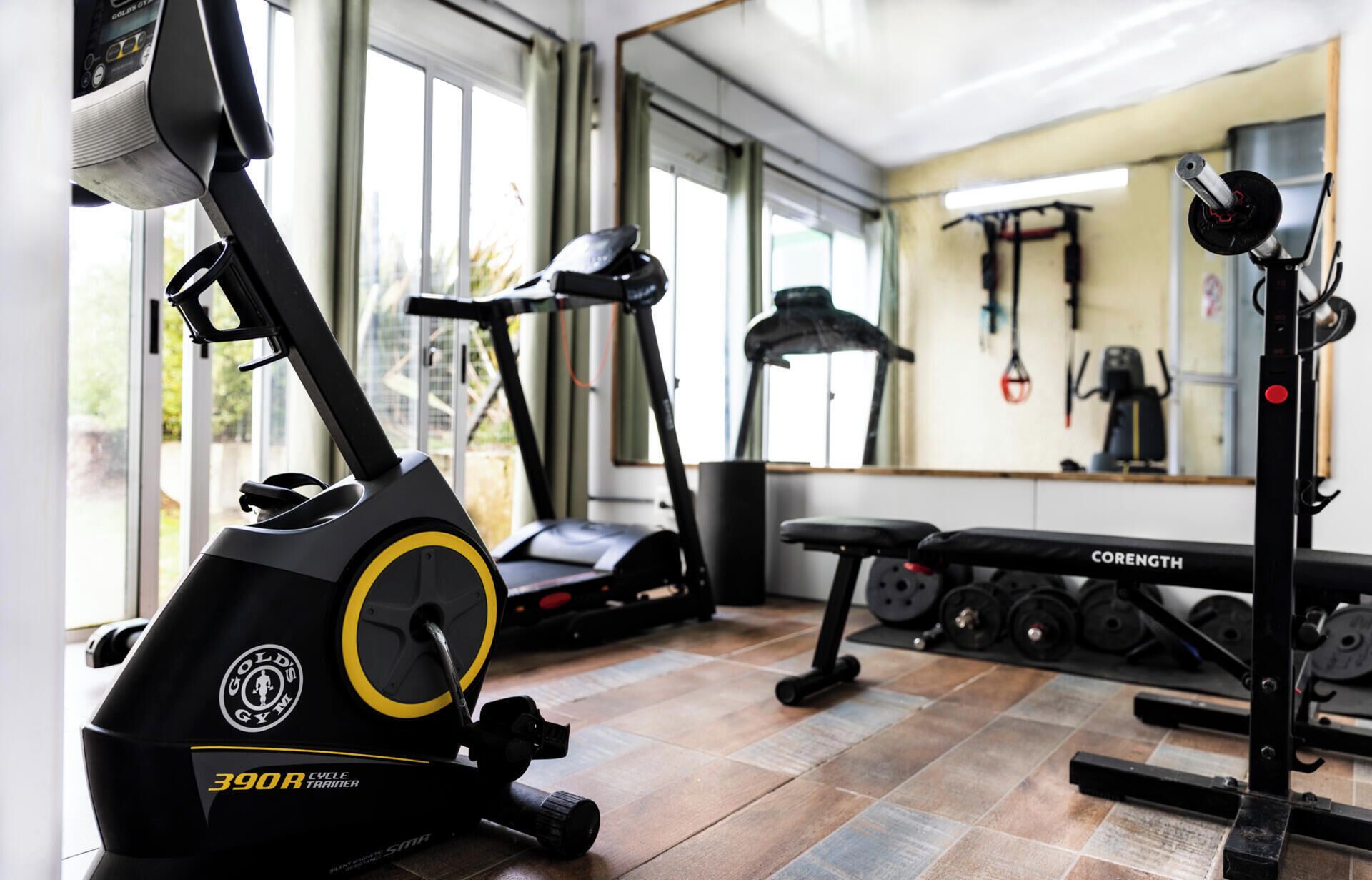 A gym with a stationary bike, treadmill, and weight bench.