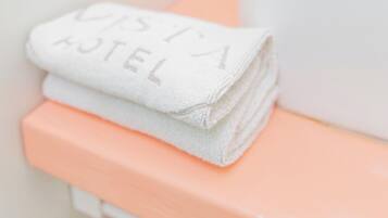 A bathroom with a white sink, a peach-colored countertop, and a folded white towel with text on it.