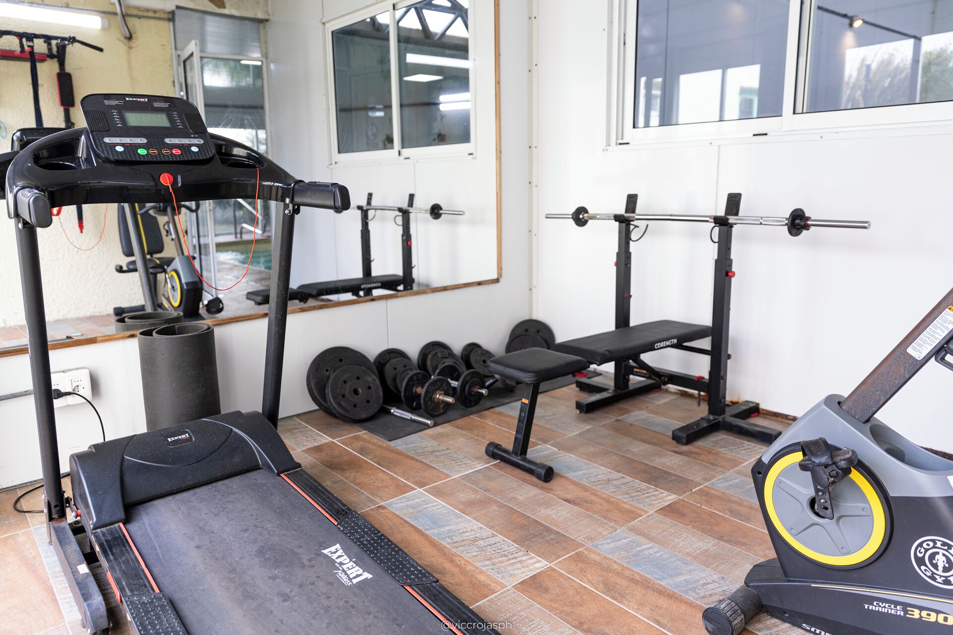 A gym with exercise equipment including a treadmill, weight bench, and dumbbells.