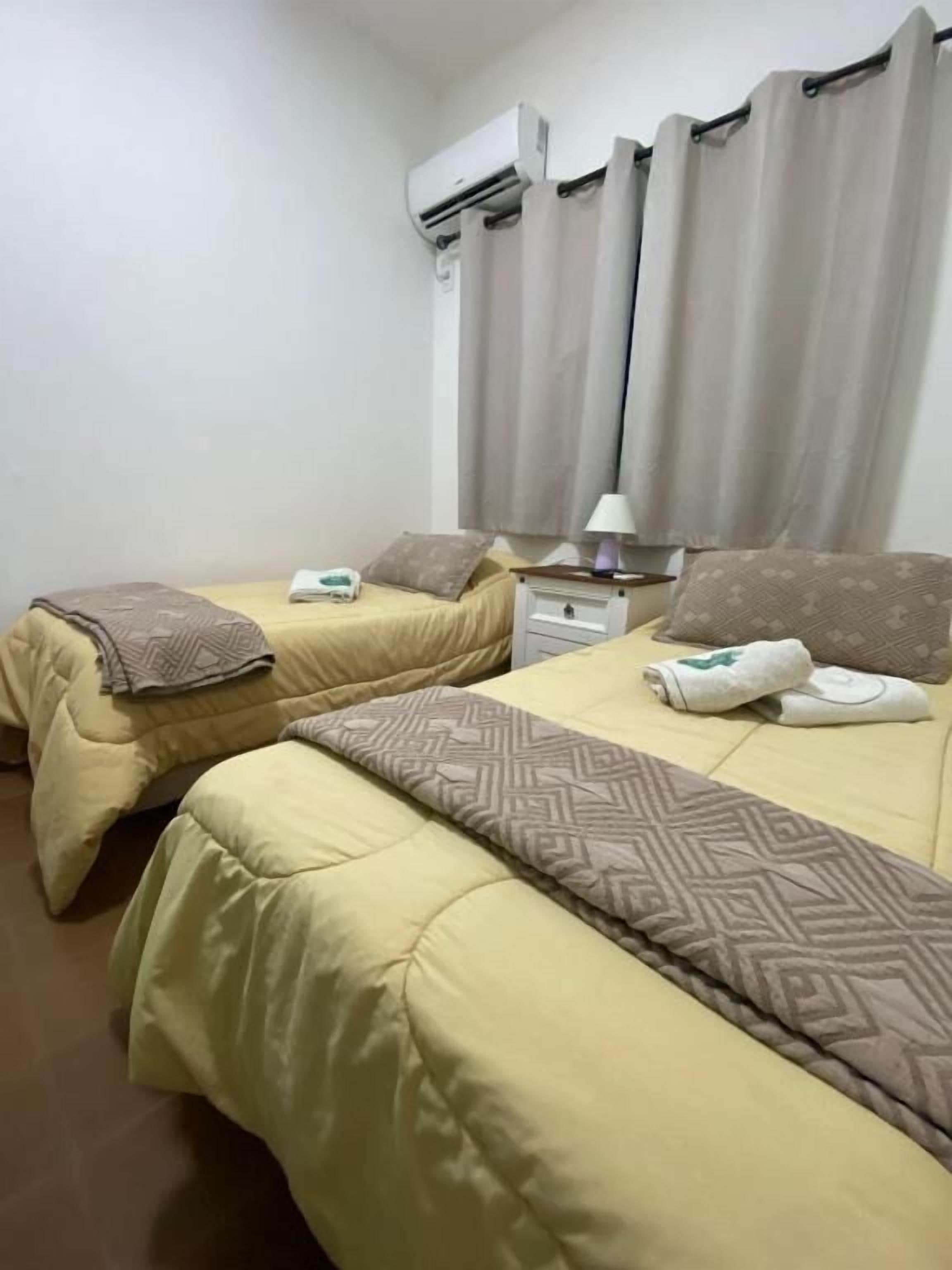 Una habitación de hotel con dos camas, una mesita de noche, una lámpara y un equipo de aire acondicionado.