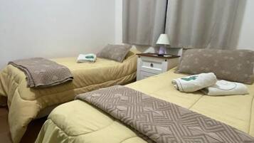 Una habitación de hotel con dos camas, una mesita de noche, una lámpara y un equipo de aire acondicionado.
