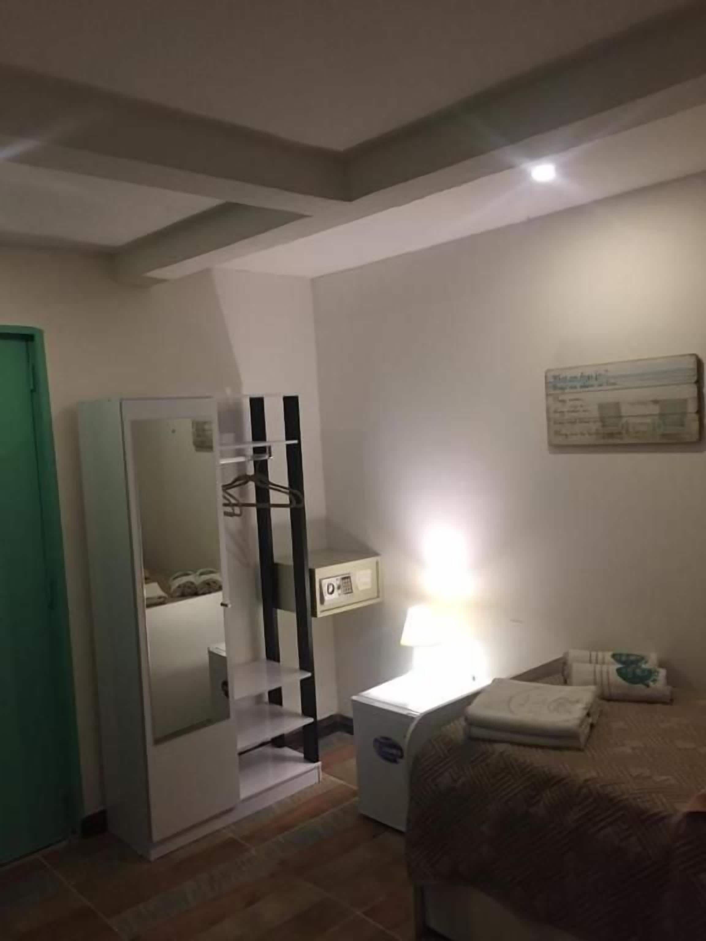 Un dormitorio con cama, mesita de noche, lámpara, armario y espejo.