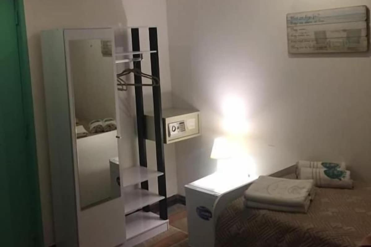 Quarto com cama, mesa de cabeceira, abajur, guarda-roupa e espelho.