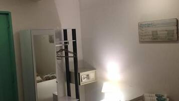 Un dormitorio con cama, mesita de noche, lámpara, armario y espejo.
