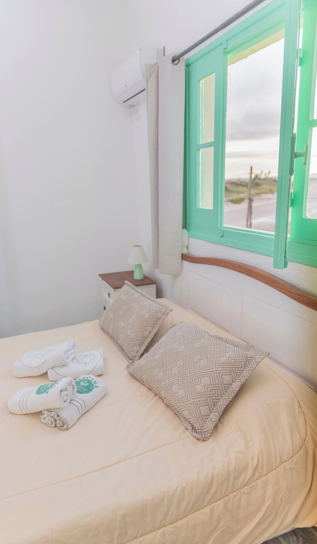 Una habitación de hotel con una cama, una mesita de noche, una lámpara y una ventana con vistas.