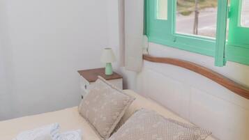 Una habitación de hotel con una cama, una mesita de noche, una lámpara y una ventana con vistas.