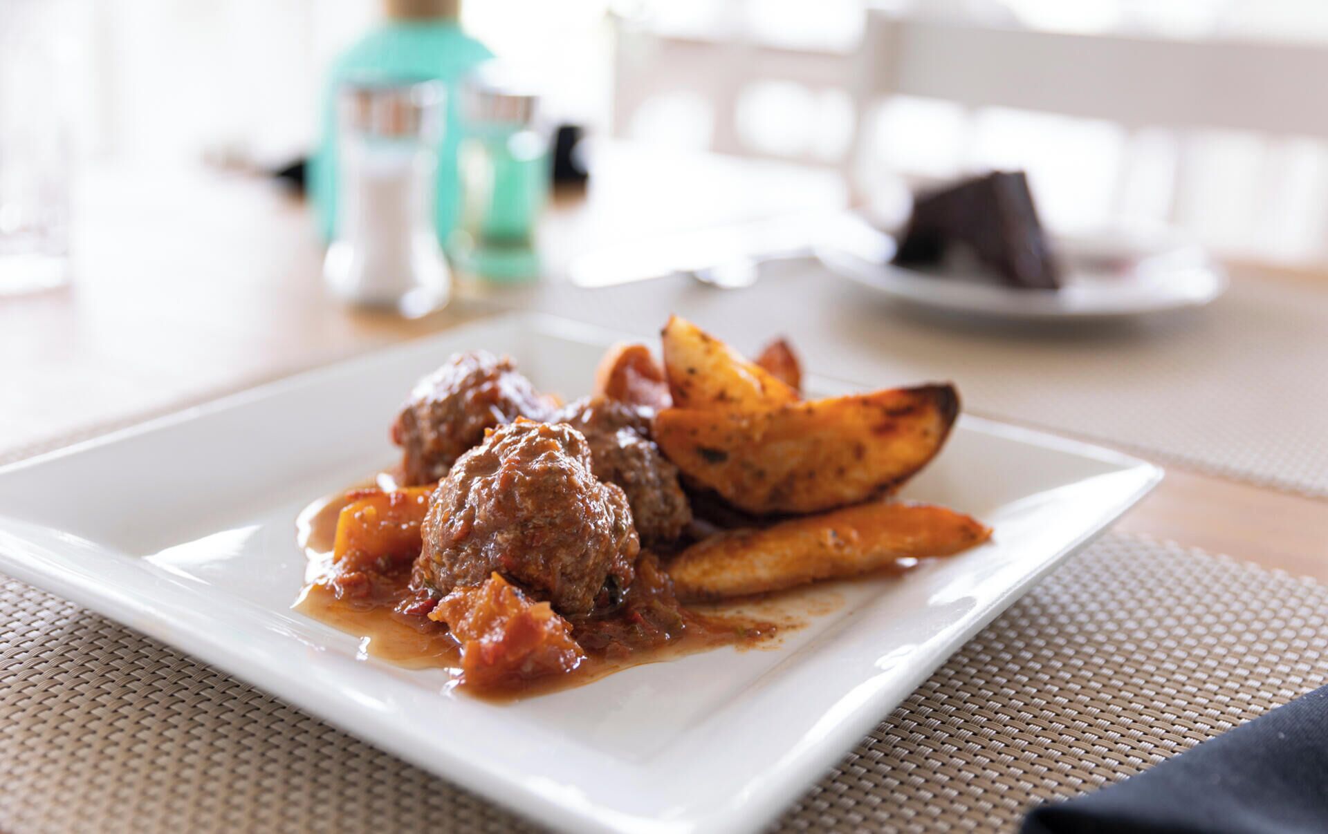 A plate with meatballs and roasted potatoes.