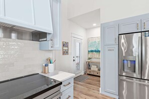 Una cocina moderna con electrodomésticos de acero inoxidable, armarios blancos y suelo de madera.