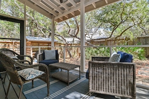 A covered outdoor seating area with wicker furniture and a view of a wooded area. - Seagrove Gardens - Community Pool & 4 Bikes! (Santa Rosa Beach)
