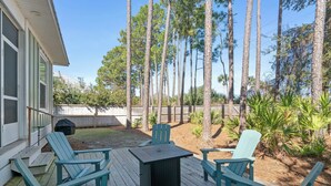 A wooden deck with four chairs and a table, surrounded by a wooden fence and tall pine trees. - Pet-Friendly 30A Cottage w/ Fenced Yard! (Santa Rosa Beach)