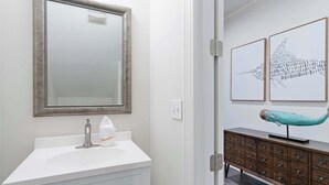 A bathroom with a white vanity, a mirror with a decorative frame, a towel dispenser, and a cabinet with drawers. - Pet-Friendly 30A Cottage w/ Fenced Yard! (Santa Rosa Beach)