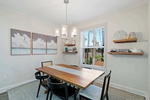 A dining area with a wooden table, black chairs, a chandelier, and artwork on the walls. - Pet-Friendly 30A Cottage w/ Fenced Yard! (Santa Rosa Beach)