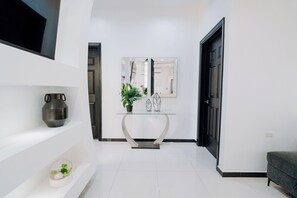 A modern hallway with a glass console table, a potted plant, and a decorative vase. - Casa Bonita Aruba | 4-Bedroom Villa with Private Pool (Oranjestad)