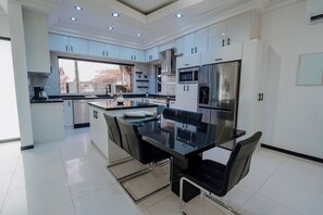 A modern kitchen with a central island, stainless steel appliances, and a view to the outside. - Casa Bonita Aruba | 4-Bedroom Villa with Private Pool (Oranjestad)