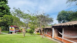 Un barrio residencial con una casa de juegos colorida, una hamaca y una casa de ladrillo.