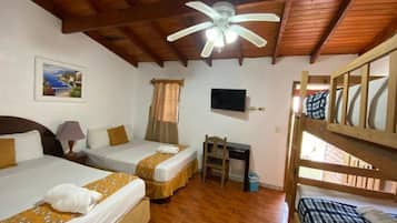 Una habitación con dos camas, un escritorio, un ventilador de techo y una televisión.