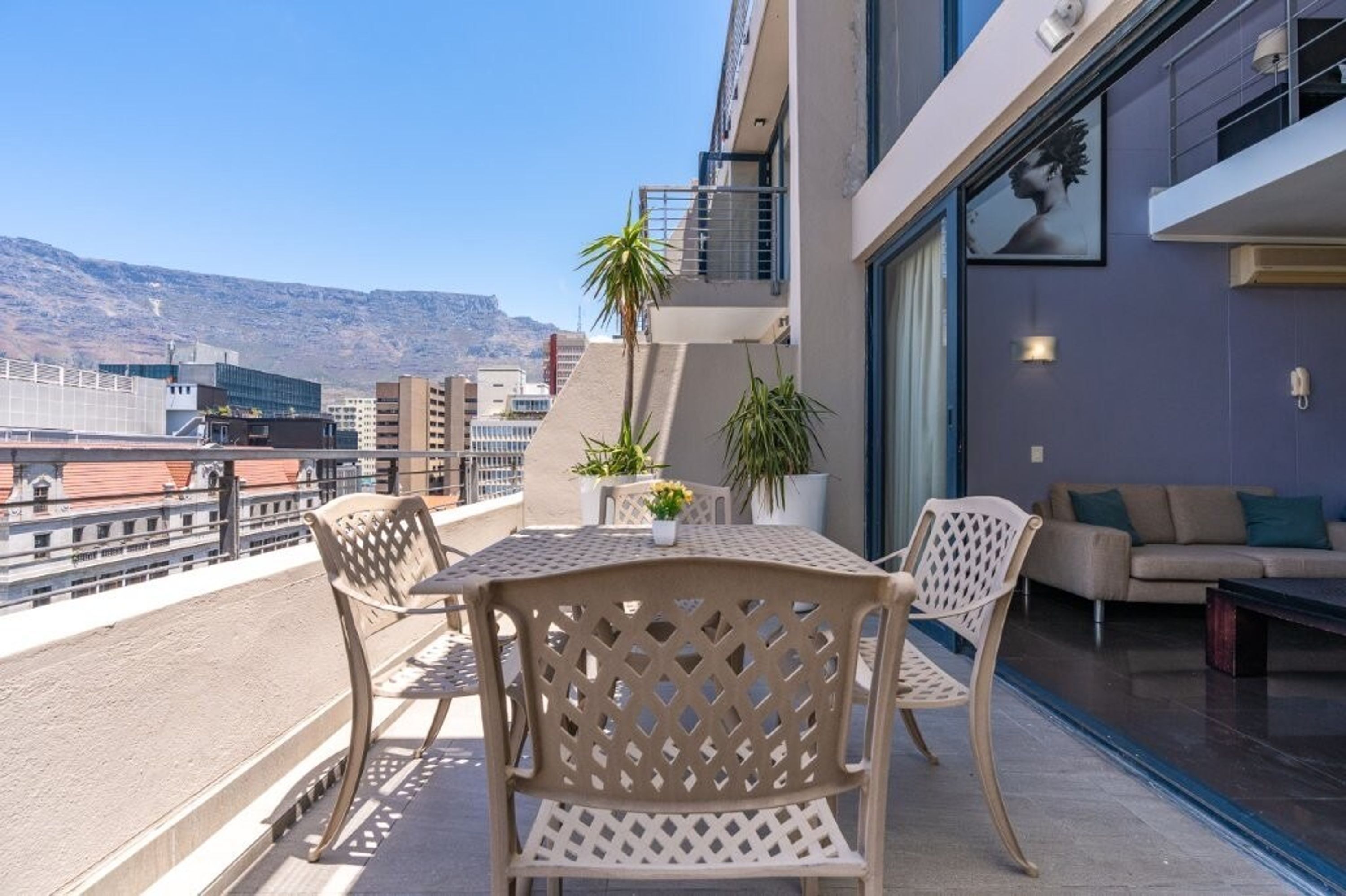 A balcony with a table and chairs, a potted plant, and a sofa.