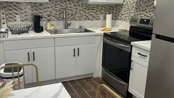 A modern kitchen with white cabinets, a stainless steel microwave, a black stove, and a dishwasher.
