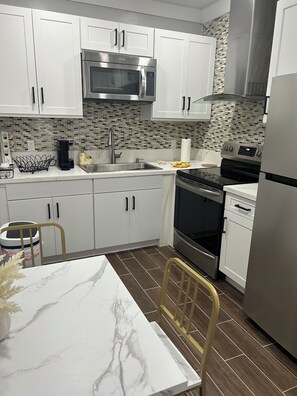 A modern kitchen with white cabinets, a stainless steel microwave, a black stove, and a dishwasher.
