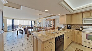 A spacious kitchen with a large island, modern appliances, and a view to the outside. - 2-bedroom Beach-front apartment in Punta Russa (Fort Myers)