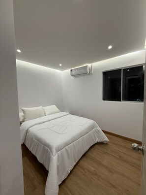 A bedroom with a bed, an air conditioning unit, a window, and a door. - 3 bedrooms | Private balcony, 5 min. from the beach (Cartagena de Indias)