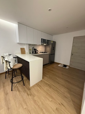 A modern kitchen with a central island, bar stools, a refrigerator, and a microwave. - 3 bedrooms | Private balcony, 5 min. from the beach (Cartagena de Indias)