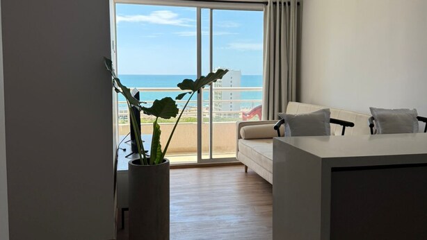 A modern living room with a large window, a sofa, a coffee table, and a potted plant. - 3 bedrooms | Private balcony, 5 min. from the beach (Cartagena de Indias)