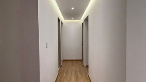 A narrow hallway with wooden flooring and white walls, featuring recessed ceiling lights and a door on the right. - 3 bedrooms | Private balcony, 5 min. from the beach (Cartagena de Indias)