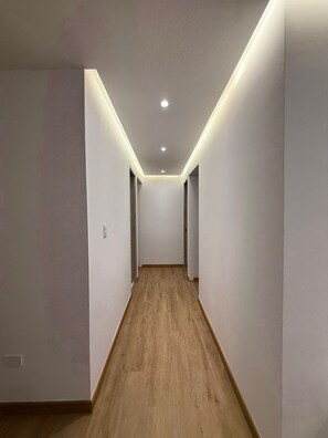 A narrow hallway with wooden flooring and white walls, featuring recessed ceiling lights and a door on the right. - 3 bedrooms | Private balcony, 5 min. from the beach (Cartagena de Indias)