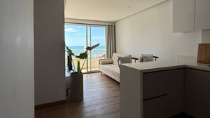 A modern kitchen with a large island, a dining area with a sofa, and a view of the sea through large windows. - 3 bedrooms | Private balcony, 5 min. from the beach (Cartagena de Indias)