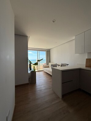 A modern kitchen with a large island, a dining area with a sofa, and a view of the sea through large windows. - 3 bedrooms | Private balcony, 5 min. from the beach (Cartagena de Indias)
