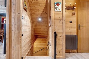 Un interior de madera con techo inclinado, una puerta con manija y un ventanal pequeño.