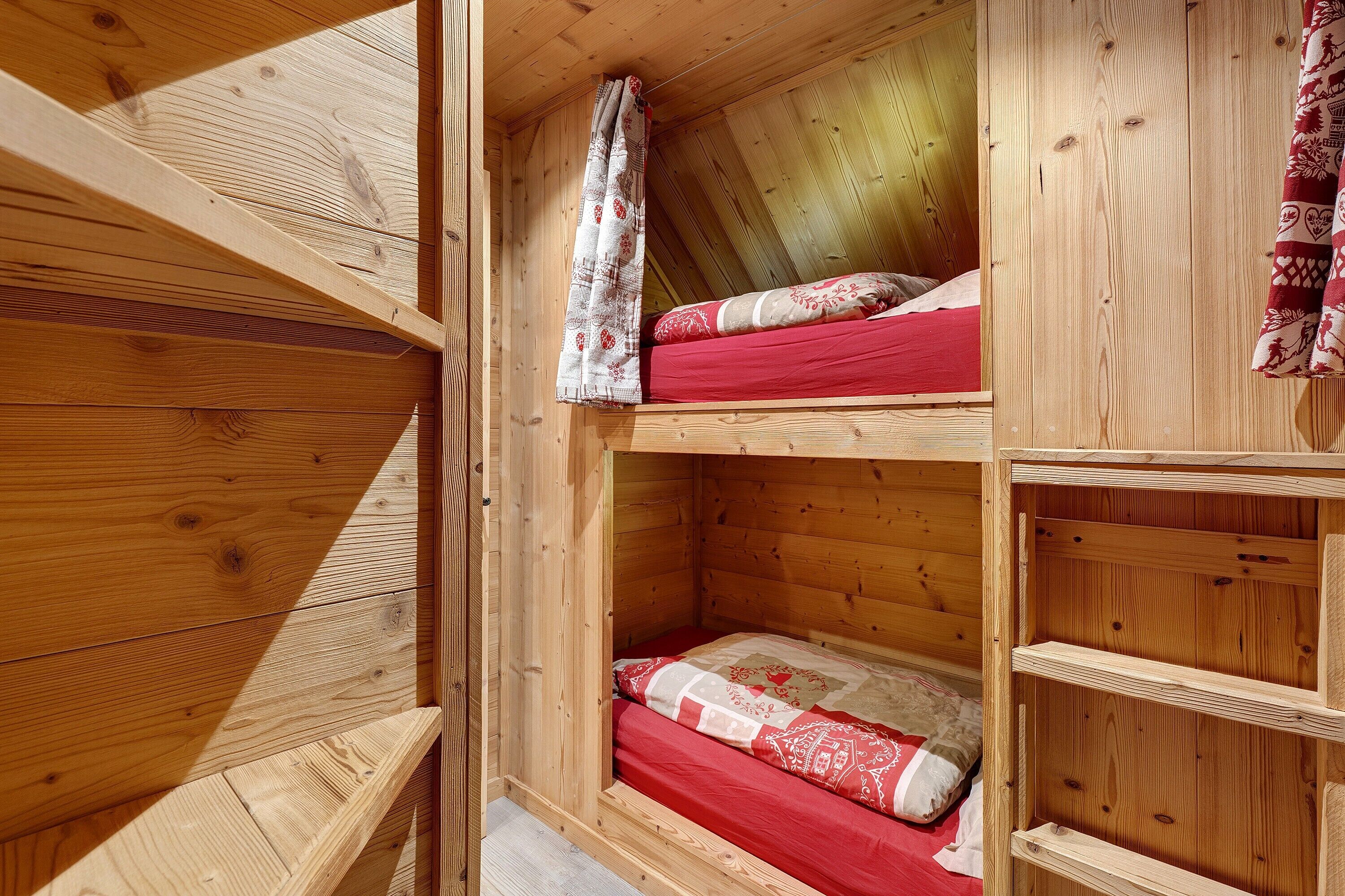 Una cabaña de madera con dos literas, una encima de la otra, y un pequeño estante de madera.