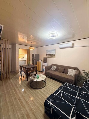 A compact living space with a dining area, a sofa, a round coffee table, and a kitchenette. - Balay Navona Matina l 3BR 2 Story Townhouse • Near SM Davao City (Davao City)