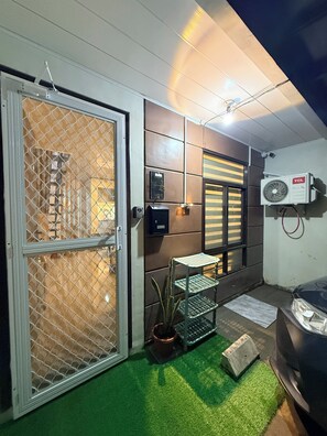 A room with a sliding door, a security keypad, a wall-mounted air conditioning unit, and a small potted plant.