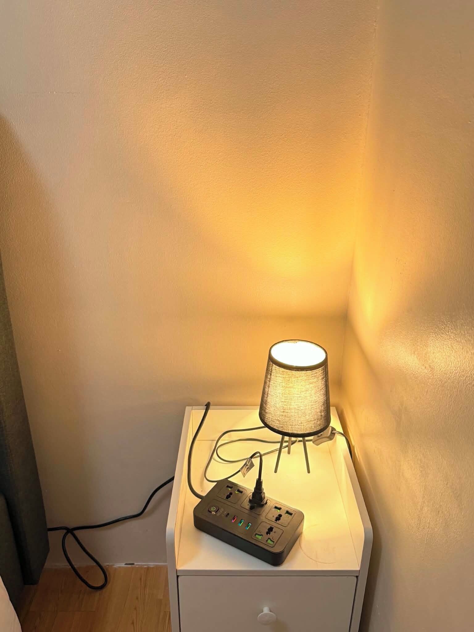 A bedside table with a lamp and a power strip.