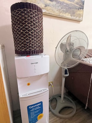A Boston Bay hot and cold water dispenser with a compressor cooling feature, placed on a white cabinet.