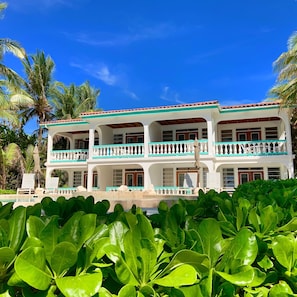 A two-story building with a balcony, surrounded by lush greenery and palm trees. - Coral Bay Villas (San Pedro)