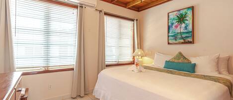 A hotel room with a bed, a desk, and a ceiling fan.